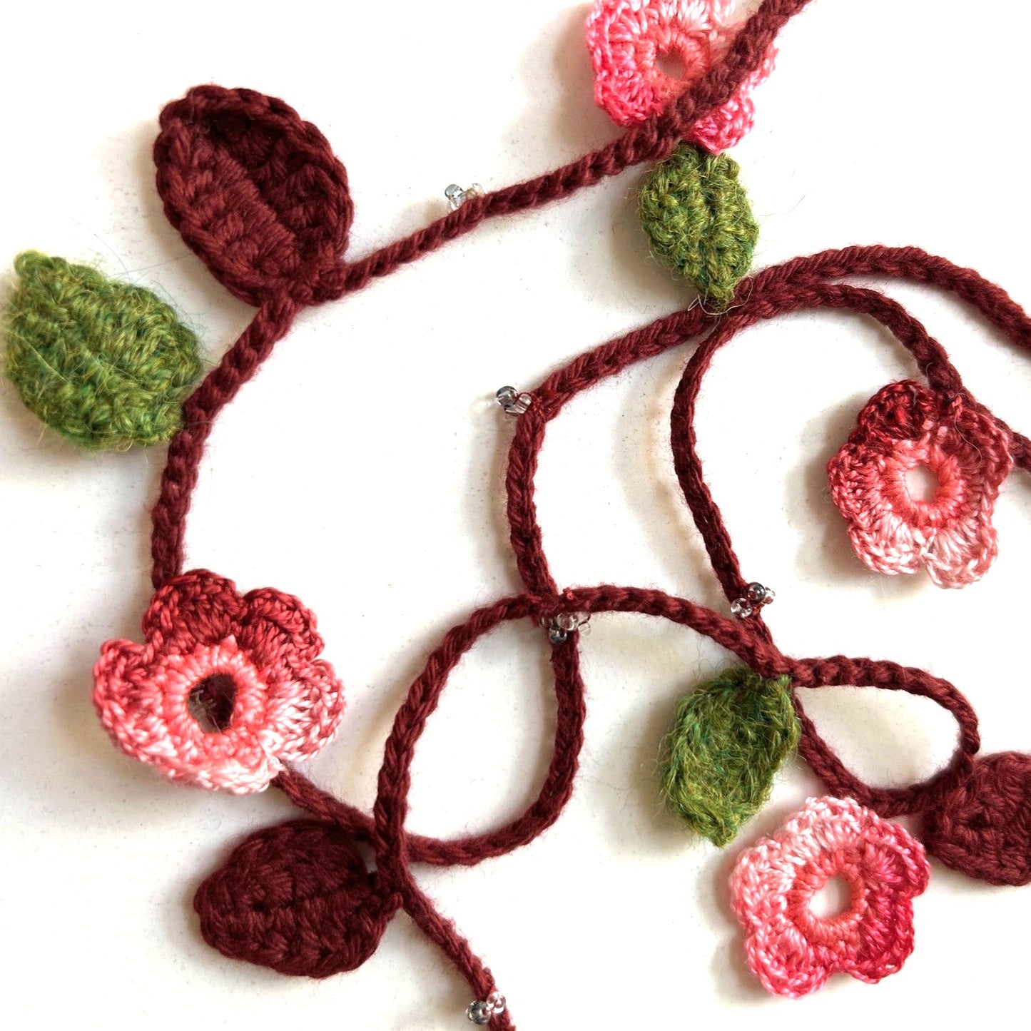 Virkat halsband/dekorband med rosa/vinröda blommor